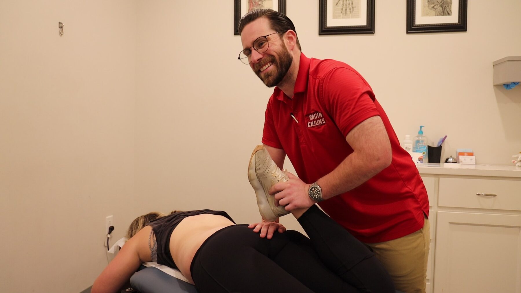 Dr. Jordan Theriot at Acadiana Pain & Performance Rehab guiding a patient through a stretch